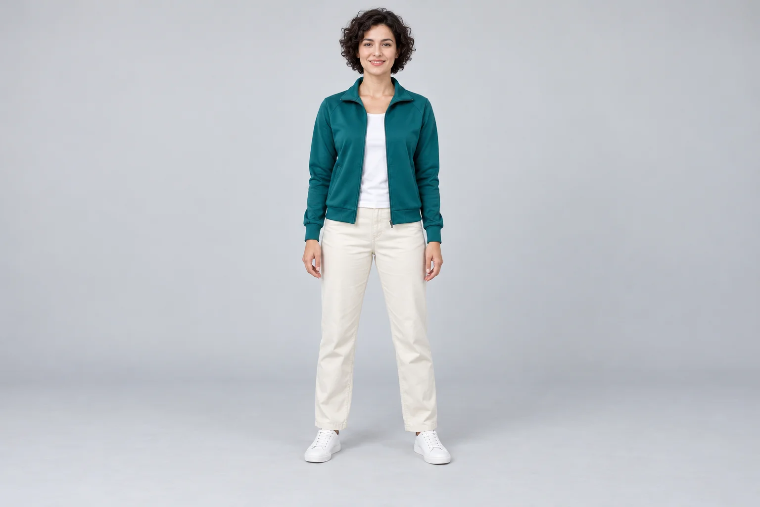 Concetto di riferimento a figura intera di una donna con capelli corti ricci, giacca verde acqua, pantaloni color crema e scarpe bianche.