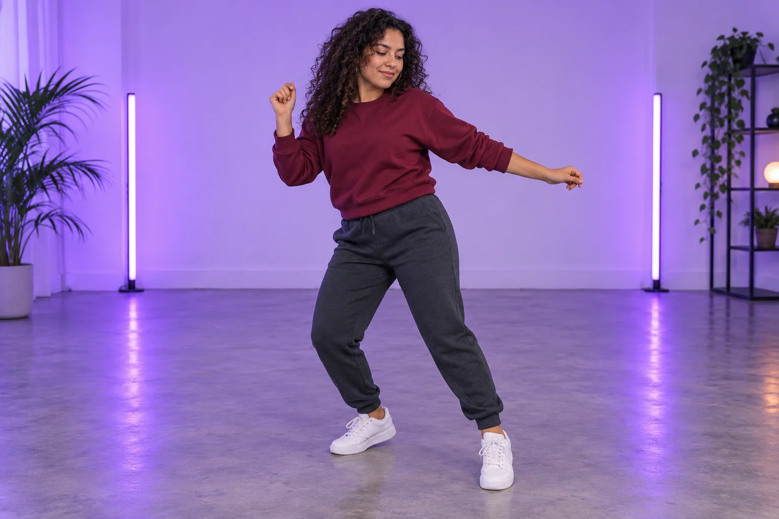 Woman in a burgundy sweatshirt dancing in a minimal violet content studio